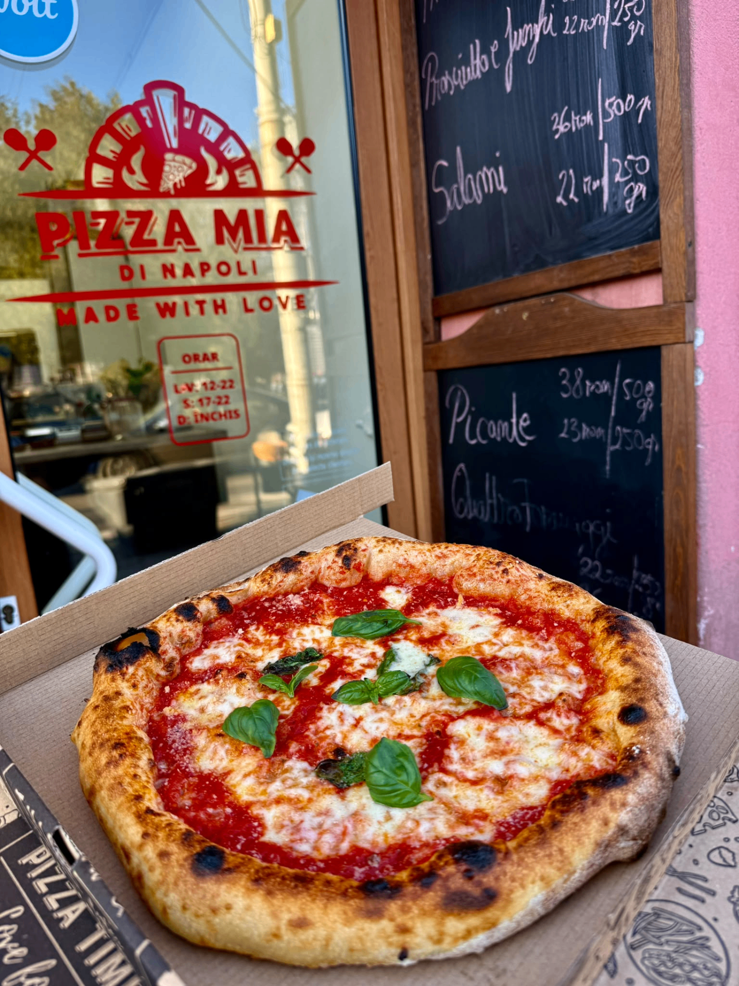 Fațada pizzeriei Pizza Mia di Napoli în Târgu Mureș, cu o pizza Margherita proaspătă în prim-plan